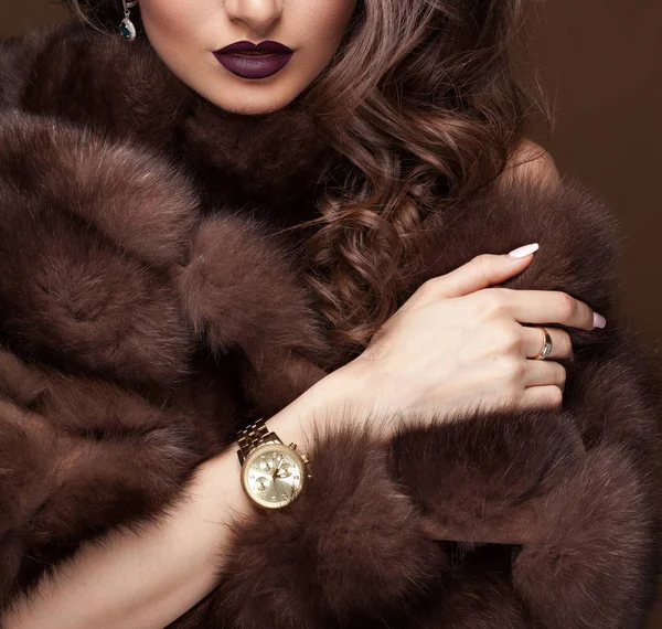 Luxury elegant woman in fur coat, golden earrings and watches. G