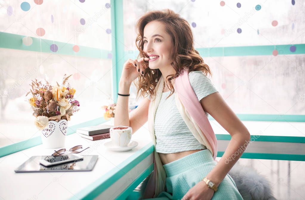 Beautiful happy pretty young woman sitting in cafe with tablet