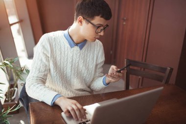 Gözlüklü genç adam onun laptop ve cep kafede kullanın. Serbest meslek