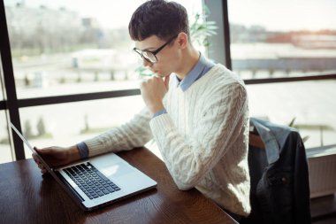 Gözlüklü genç adam onun laptop ve cep kafede kullanın. Serbest meslek