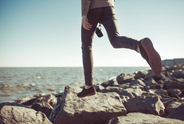  Genç adam hipster kot pantolon ve ayakkabı kayalarda atlama 