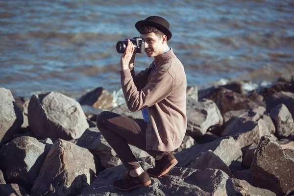 Un joven hipster tomando fotos cerca del mar. La ramita soleada —  Fotos de Stock