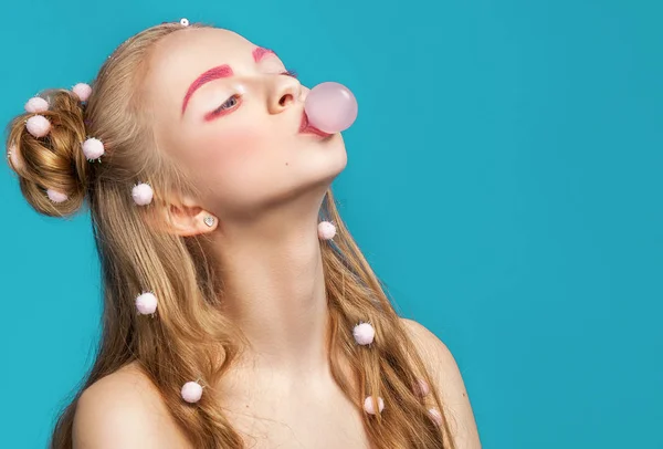 Jovem mulher bonita e engraçada soprando chiclete rosa sobre blu — Fotografia de Stock