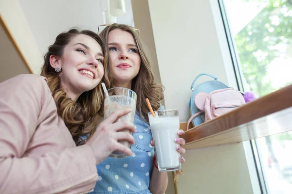 Deux belles jeunes femmes dans un café buvant des coctails et riant — Photo