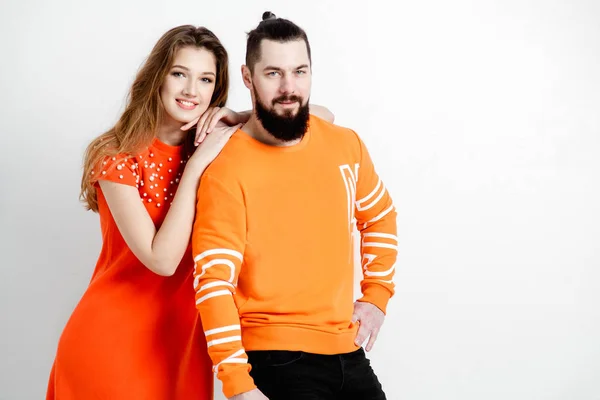 Happy fashion couple in trendy spring clothes. Orange dress and sweashirt. White background.