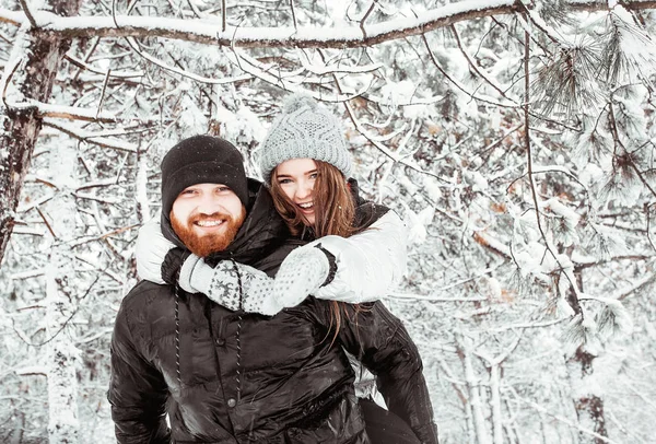 Feliz casal jovem apaixonado se divertindo na floresta de neve de inverno. Ganhar — Fotografia de Stock