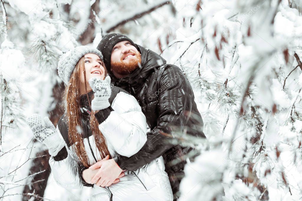 Happy young couple in love having fun in winter snow forest. Win