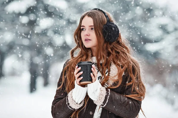 Happy young woman with cup of coffee in snowy winter day. Girl e — Stock Photo, Image