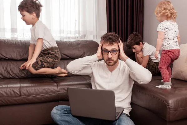 Young busy father trying to work at home with his children. Self isolation. Stay home concept. Freelancer.
