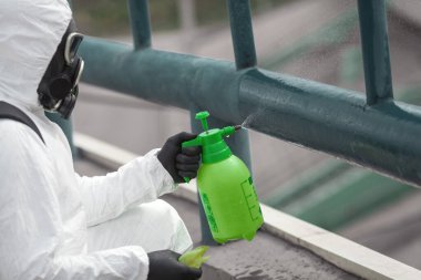 Karantina, koronavirüs enfeksiyonu. Koruyucu ekipman kullanan bir adam şehirde dezenfektanla dezenfekte ediyor. Sokakta temizlik ve dezenfeksiyon. Koruyucu giysi ve maske. Salgın.