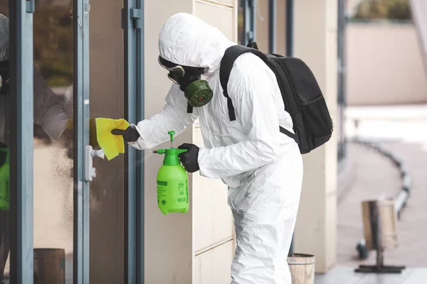 隔離コロナウイルス感染症 防護具を着た男が街中の噴霧器で消毒する 通りでの清掃と消毒 防護服とマスク — ストック写真