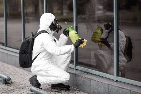 코로나 바이러스 장비를 도시에 스프레이로 길거리에서 청소하고 소독하는 보호용 수트와마스크 — 스톡 사진