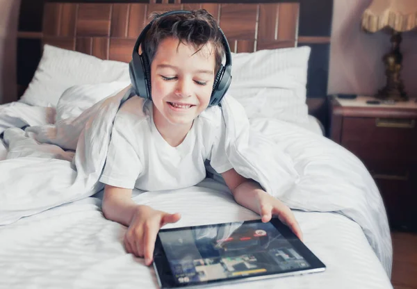 A boy using a digital tablet on the bad watching or playing digital tablet. Home education. Stay home concept. Preschool children learning.