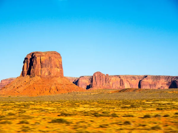 纪念碑谷提供了也许是美国西部最持久和决定性的形象 孤立的红色中间点和扣子被空旷的 沙质的沙漠包围着 那是纳瓦霍部落的土地 — 图库照片