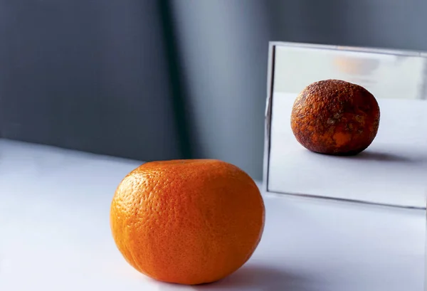 桌上新鲜的橙子倒映在镜子里 就像烂了的坏水果 关于年轻和老年 内在美 谎言的概念性照片 — 免费的图库照片