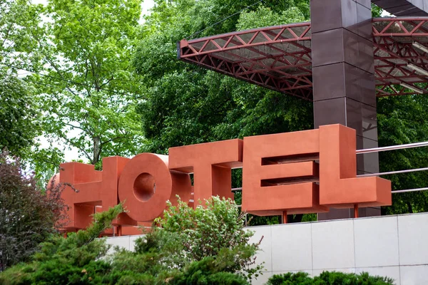 Hotel entrance is in green leaves and trees. There are big letters 