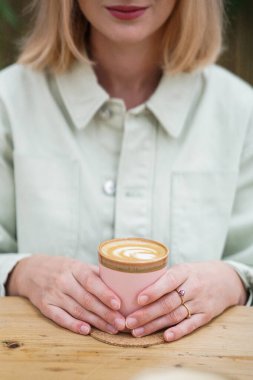 Güzel kız elinde pembe ve yeşil kupa tutuyor..