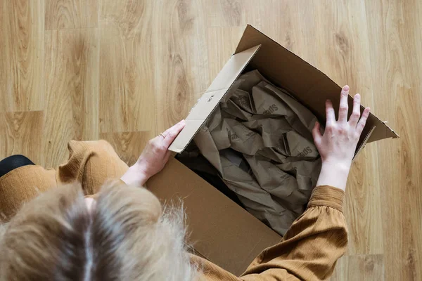 Müşteri olan genç bir kadın paket hazırlıyor. Bant ve makas kullanarak. Kız tüketici yerde karton kutu tutuyor..