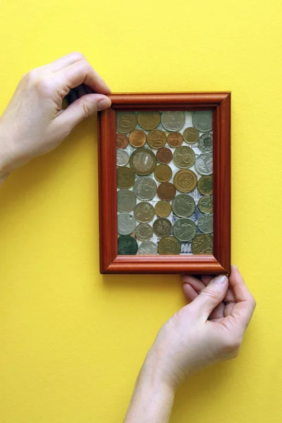 hands hang a picture with coins, money worship, the cult of money