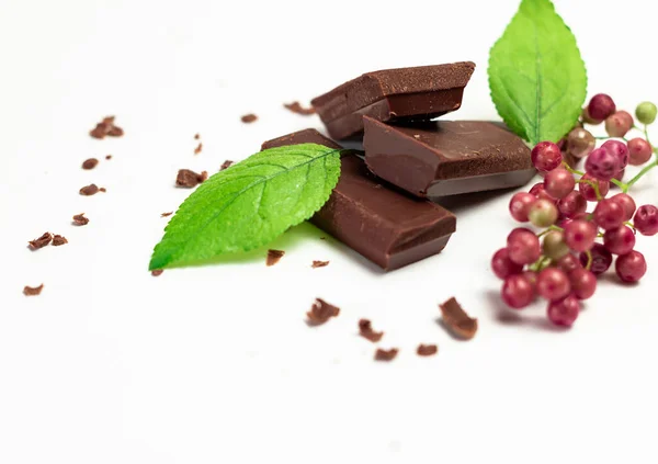 Pieces Chocolate White Background Accompanied Chocolate Shavings Red Berries Green — Stock Photo, Image