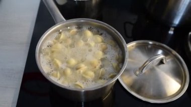Tavada Ravioli, kaynar su, gümüş metal arka plan. Pelmeni pişirmek, kıyma ile doldurulmuş Rus köfteleri, ev mutfağındaki seramik ocağın çelik güvecinde. Varenyky, vareniki.