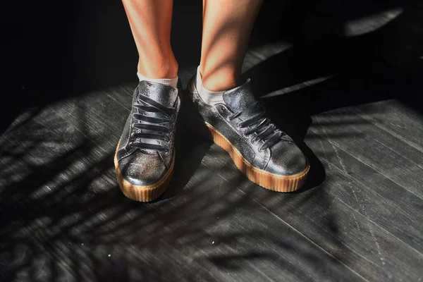 Feet in the floor. Model with a pair of fashion silver female shoes. Selective focus.