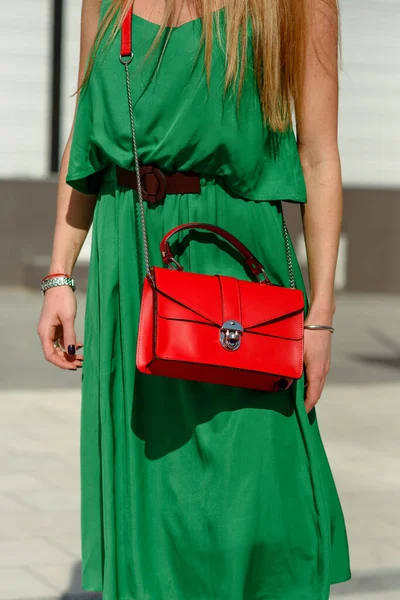 屋外でバッグを持っている女の子 トレンドの服の女性で緑のドレスで赤バッグ 女の子は路上で非常にダイナミックなポーズ — ストック写真