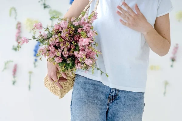 Chica con una bolsa de mimbre y flores bailando en un estudio brillante — Foto de Stock