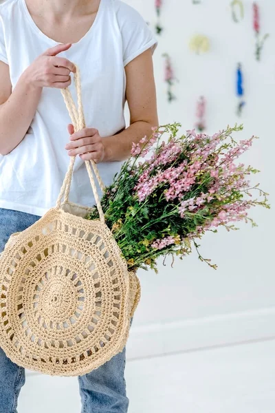 Menina com um saco de vime e flores dançando em um estúdio brilhante — Fotografia de Stock