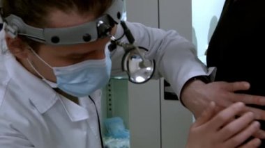 Genç bir hastayı muayene eden erkek bir otolarolog.