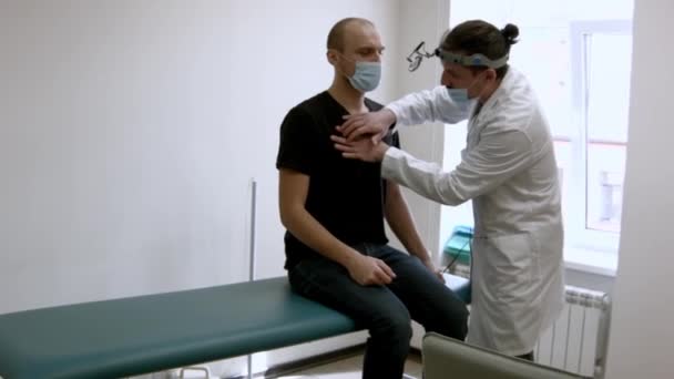 Jovem Otorrinolaringologista Examinando Paciente Masculino Seu Gabinete — Vídeo de Stock