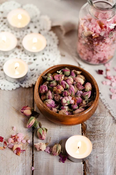 Concept of spa treatment with roses. Dry flowers in a bowl, herbal tea, towel, candles as decor. Atmosphere of relax and pleasure, comfort, anti-stress and detox procedure. Luxury lifestyle.