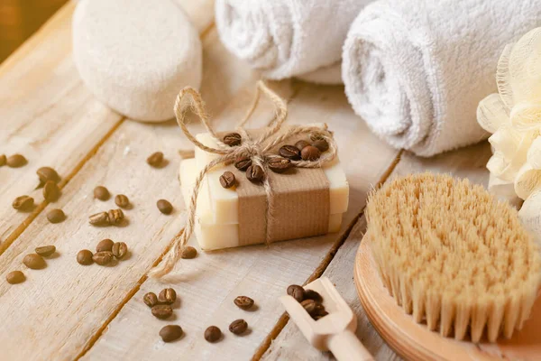 Concept of home natural organic skin care. Handmade soap bars with coffee used as gentle scrub. Brush to increase anti-cellulite effect. Relax pleasant treatement. Wooden background close up