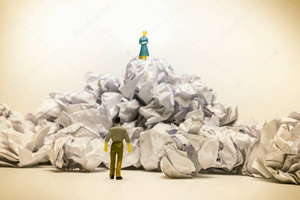 The man look at wonmen on top of crumpled papaer heap and he wants to get close to her.toy figure