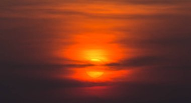 Duman bulutları turuncu güneşi kırmızı ışıkla kapladı.