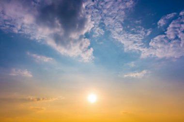 Mavi gökyüzünde turuncu ışık ve yumuşak bulutlarla gün batımı