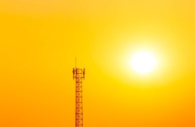 Turuncu gökyüzünde güneş gören iletişim direği