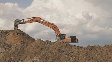 Kazı makinesi, zemin. Bir kazıcı engin kuzey gökyüzüne karşı toprağı kazıyor..