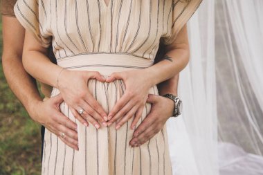 Hamile bir kızın karnı ellerle kapanır.