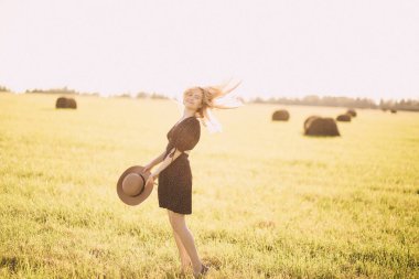 Gün batımında tarlada gülümseyen kız şapkasıyla