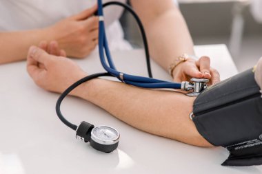 Doktor kontrol etmek için stetoskoplu sfenometre kullanıyor.