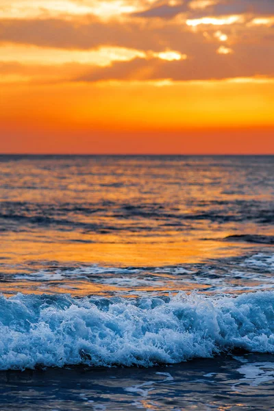 Köpüklü güzel dalgalar, denizin batan güneşiyle aydınlanıyor. Gün batımında dalgalı deniz yüzeyinin dokusu.