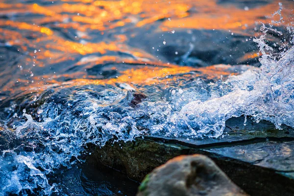 Köpüklü güzel dalgalar, denizin batan güneşiyle aydınlanıyor. Gün batımında dalgalı deniz yüzeyinin dokusu.