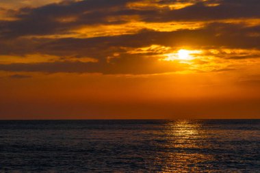 Denizde güzel bir gün batımı. Batan güneşin ışınları parlıyor