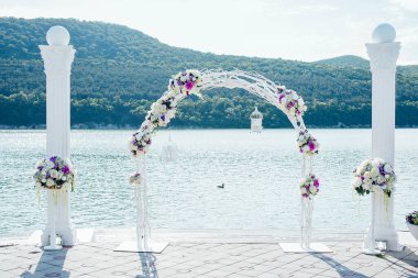 Bir düğün töreni için çiçeklerle süslenmiş zarif beyaz kemer.