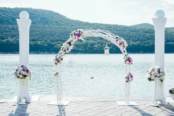 Bir düğün töreni için çiçeklerle süslenmiş zarif beyaz kemer.