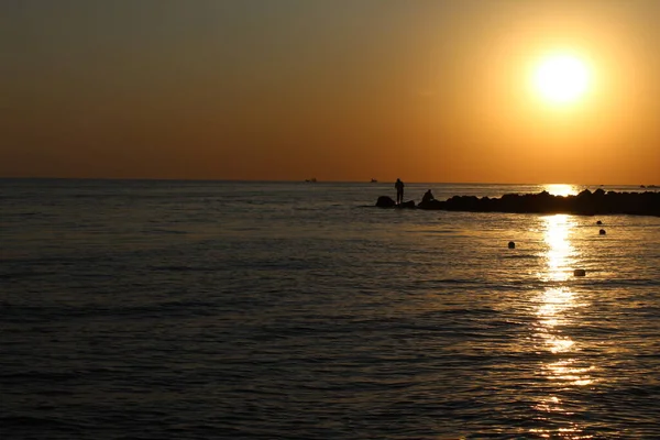 Gün batımında denizin üzerinde balıkçı.