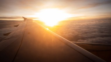 Gün batımında bulutlu bir havada uçak kanadı. Altın bizim. Seçici odaklanma. Boşluğu kopyala.