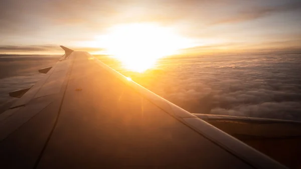 Gün batımında bulutlu bir havada uçak kanadı. Altın bizim. Seçici odaklanma. Boşluğu kopyala.