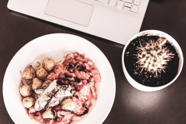 Laptop ve farenin çalışma alanında öğle yemeği. Kaktüs süslemeli deniz salatası tabağı. Zenital görüş. Seçici odak